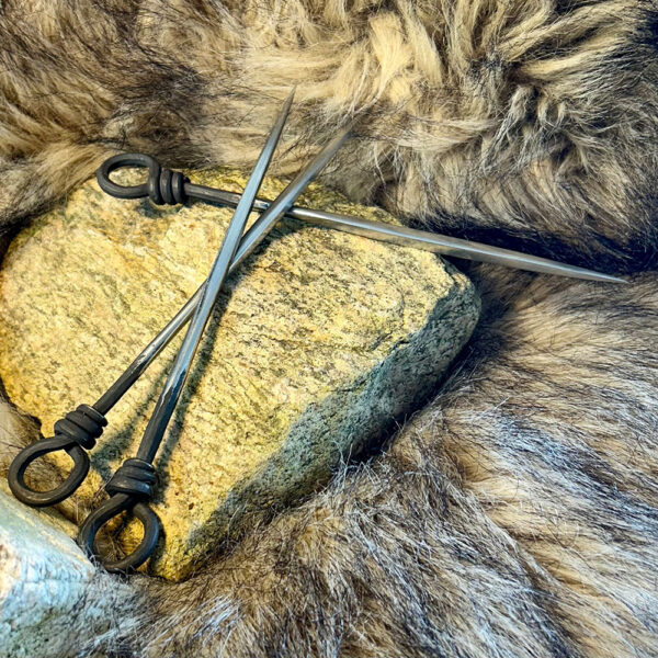Medeltida ätpinne i rostfritt stål liggandes på sten och päls